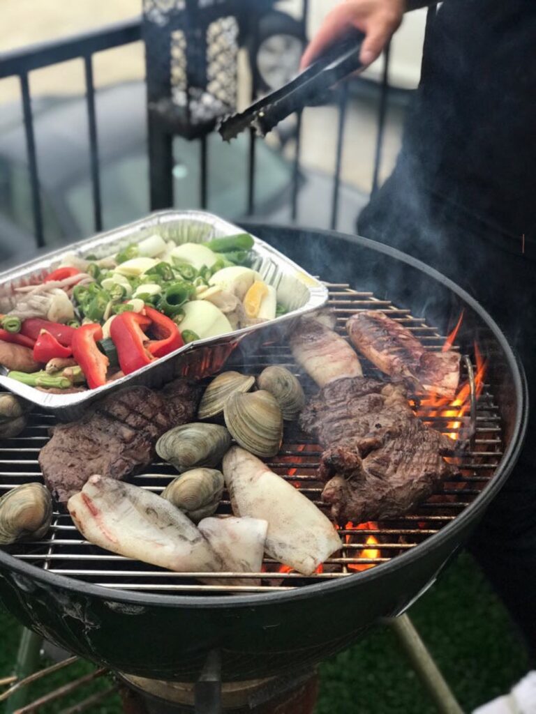숯불 위에서 굽고 있는 조개와 고기, 채소